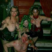 Sister Nagsters at the Double Door, Chicago IL with Dagon Bytes and Mistress Cherish is of four people. In the background are three corsetted women dressed like medusa and crouching down in front of them is a topless man dressed like Pan