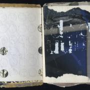 DDD: Random Journal Page 163 by Laura Chenault. This sketchbook spread has a white perforated left side with some of the holes punched out to reveal a map underneath. The white side is a blue and gray with deteriorating transfer letters "ddd" and "uuu" in white ink.